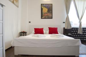 a white bed with red pillows in a bedroom at Studio apartment with a view of Ban Jelačić Square in Zagreb