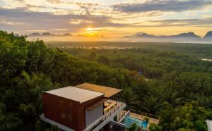 a house in the middle of a forest with the sunset at Ao Luek Panoramic Pool-SHA Plus in Ao Luk