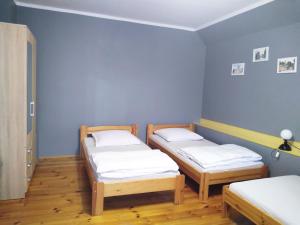 three beds in a room with blue walls and wooden floors at Agroturystyka Natalia in Bukówka