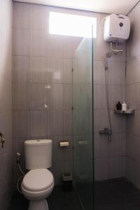 a bathroom with a toilet and a glass shower stall at Cakra House in Denpasar