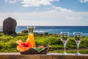 einen Tisch mit zwei Gläsern Wein und eine Schüssel Blumen in der Unterkunft Ngahu Bungalows Alojamiento Frente al Mar en el centro de Rapa Nui in Hanga Roa