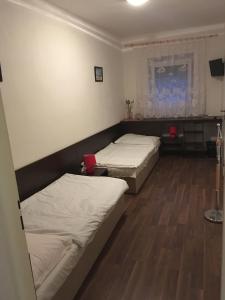 two beds in a room with wooden floors at HARRYS City Motel in Komárno