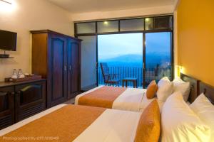 a hotel room with two beds and a balcony at Ceyloni Panorama Resort in Kandy