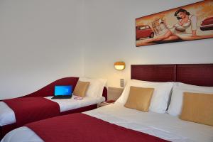 a hotel room with two beds and a laptop on a desk at Hotel Aldebaran in Rimini