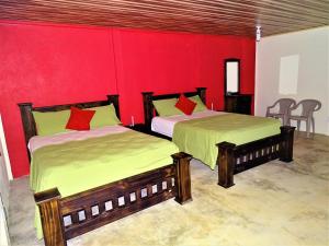 duas camas num quarto com uma parede vermelha em Hostel Osa Tucan Drake em Drake