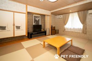 a living room with a table and a tv at Sora Hotel Karuizawa Outlet in Karuizawa