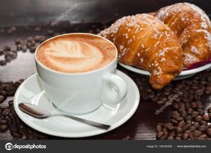 una taza de café y croissants y granos de café en Palazzo Tritone & Abagnale en Sorrento