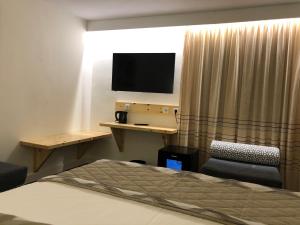 a hotel room with a bed and a television at Acrotel Sofia's Guest House in Sidherás