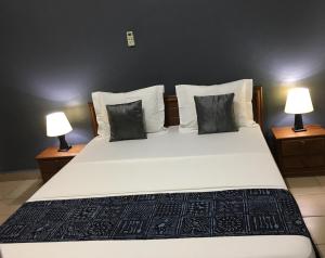 a bedroom with a large white bed with two lamps at Bolo Residence Douala in Douala