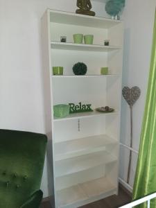 a white book shelf in a room with a green chair at Unterkunft mit Wohlfühleffekt und Flair in Rehburg-Loccum