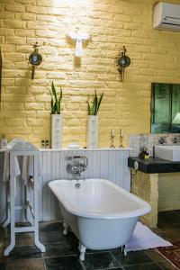 a white bath tub in a bathroom with a yellow wall at Somerset Stables in Graaff-Reinet