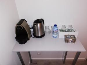 a white table with a coffee maker and a bottle of water at Le petit nid douillet in Trescléoux