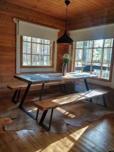 a dining room with a table and benches and windows at PyhäBerry in Pelkosenniemi