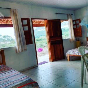 ein Zimmer mit einer Tür zu einem Schlafzimmer mit einem Fenster in der Unterkunft Pousada Serra Aquarela - Mini casas in Ibicoara