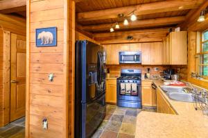 eine Küche mit Holzschränken und einem schwarzen Kühlschrank in der Unterkunft Smokies Overlook Lodge in Waynesville