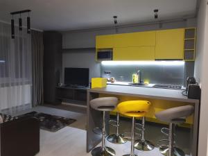 a kitchen with yellow cabinets and yellow stools at Travel Homzzz Central Apartments - Piata Trandafirilor in Târgu-Mureş