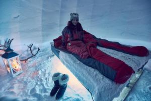 a woman sitting on a bed in the snow at Lucky Ranch Snow Igloos in Pyhätunturi