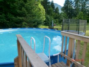 a swimming pool with a deck and a chair next to it at Garten- & Loggia-Appartement HERRENHAUS in Dellach im Drautal