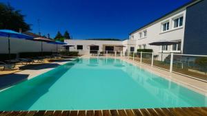 a large blue swimming pool next to a building at Citotel Hôtel Le Capricorne in Marmande