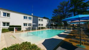 a large swimming pool with an umbrella and chairs at Citotel Hôtel Le Capricorne in Marmande +40 photos