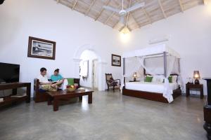 two people sitting in a room with a bed and a tv at Ceylon Olive Galle in Galle