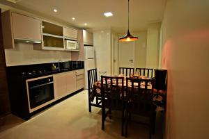una cocina con mesa y sillas y una cocina con armarios blancos. en Morada Pinheiro 160m da Praia, en Bombinhas