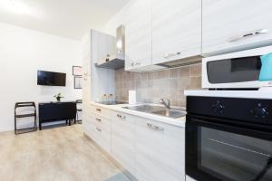 a kitchen with white cabinets and a sink and a microwave at Renovated Flat Subway Yellow Line in Milan