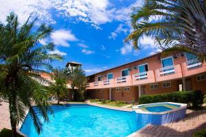 um resort com piscina e palmeiras em Pousada Marbella em Búzios