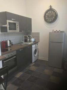 a kitchen with a refrigerator and a clock on the wall at charmant studio Pont-Audemer in Pont-Audemer +3 photos