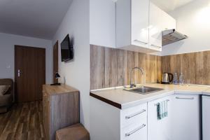 a kitchen with white cabinets and a sink at Pokoje Gold Centrum in Koszalin +7 photos