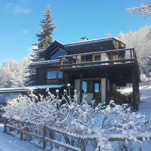 une maison dans la neige avec un banc devant elle dans l'établissement La Sauvagine B&B Skis aux pieds, aux Orres