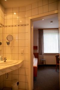 a hotel room with a bathroom with a sink and a bed at Hotel Waldfrieden in Emmelshausen