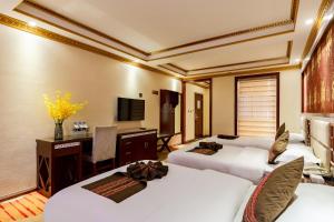 a hotel room with two beds and a desk and a television at Floral Hotel · Shangri-la Blue Sky in Shangri-La