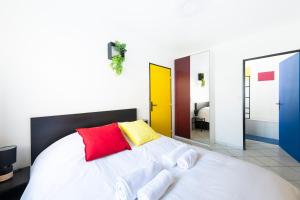 ein Schlafzimmer mit einem weißen Bett mit roten und gelben Kissen in der Unterkunft Appartement entier - Le mondrian - 1ch Check-in 24h in Villeurbanne