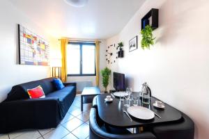 ein Wohnzimmer mit einem schwarzen Sofa und einem Tisch in der Unterkunft Appartement entier - Le mondrian - 1ch Check-in 24h in Villeurbanne