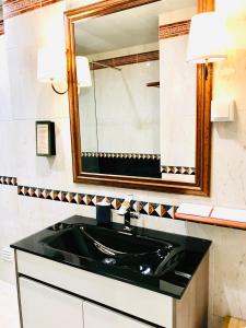 Un baño con un lavabo negro y un espejo. en Alameda Garden, en Faro