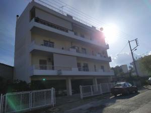 a white building with a car parked in front of it at Stamatis Big Apartment in Spata