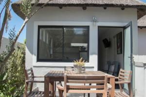 a patio with a table and chairs and a window at The Yacht in Hermanus