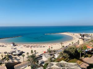 uma vista para uma praia com guarda-sóis e para o oceano em Royal on the Sea em Netanya