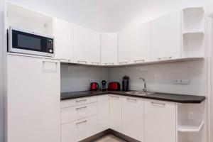 a white kitchen with white cabinets and a microwave at Contemporary City Apartment Váci Utca in Budapest