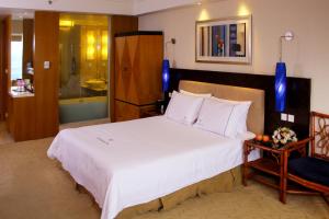 a bedroom with a large white bed and a chair at Huizhou Kande International Hotel in Huizhou
