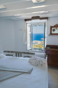 a bedroom with a white bed and a window at SeaScapeHome Serifos in Serifos Chora