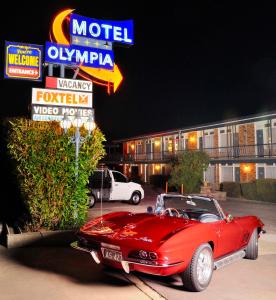 a red car parked in front of a motel at Olympia Motel in Queanbeyan