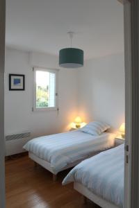 two beds in a bedroom with a window and two lamps at Cape Cod in Wimereux