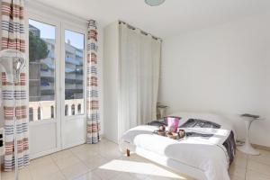 a white bedroom with a bed and a window at Appartements Cannes in Cannes