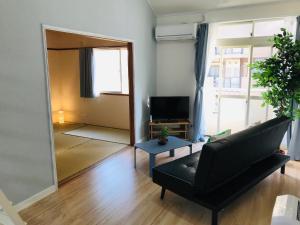 ein Wohnzimmer mit einem schwarzen Sofa und einem Spiegel in der Unterkunft It's Kasuga Town B Building / Vacation STAY 60078 in Kasugabaru