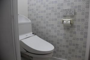 ein Badezimmer mit einem weißen WC und einer Fliesenwand in der Unterkunft It's Kasuga Town B Building / Vacation STAY 60078 in Kasugabaru