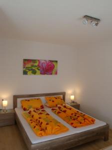 ein Bett mit orangefarbenen Kissen und ein Gemälde an der Wand in der Unterkunft Haus Matthias in Umhausen