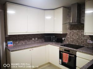 a kitchen with white cabinets and a stove top oven at RICHFLO Holiday Rentals in Manchester