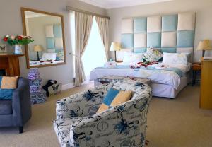 a bedroom with a bed and a couch and a mirror at Fly Me To The Moon Guesthouse in Mossel Bay